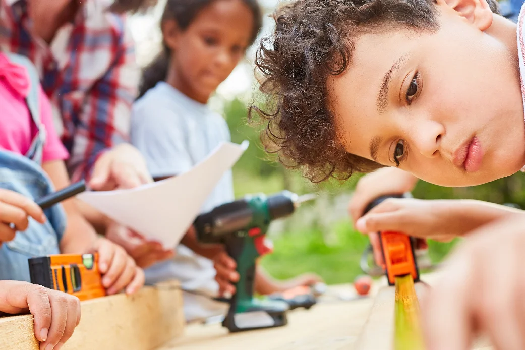 Kind misst Holz mit Zollstock